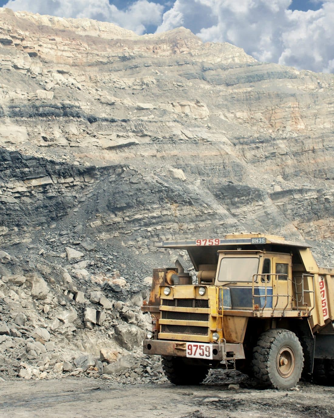 Haul truck working a benched open-pit mine face.